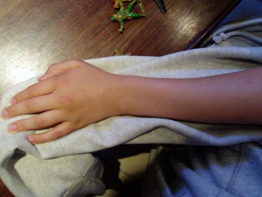 A left forearm on a grey hoodie lying on a table
